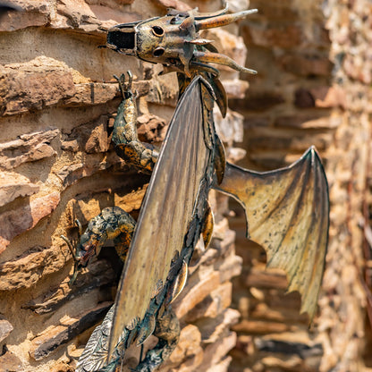 Metallic dragon sculpture on a textured stone wall
