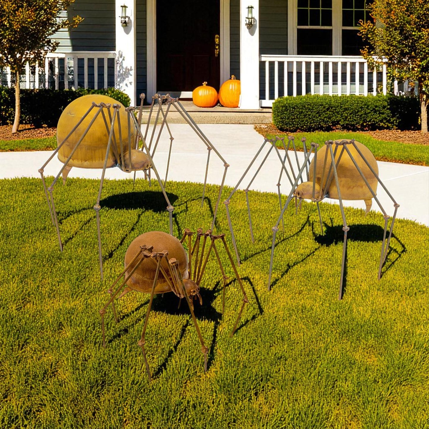 Set of three metal spider garden sculptures with distressed iron finish displayed on lawn