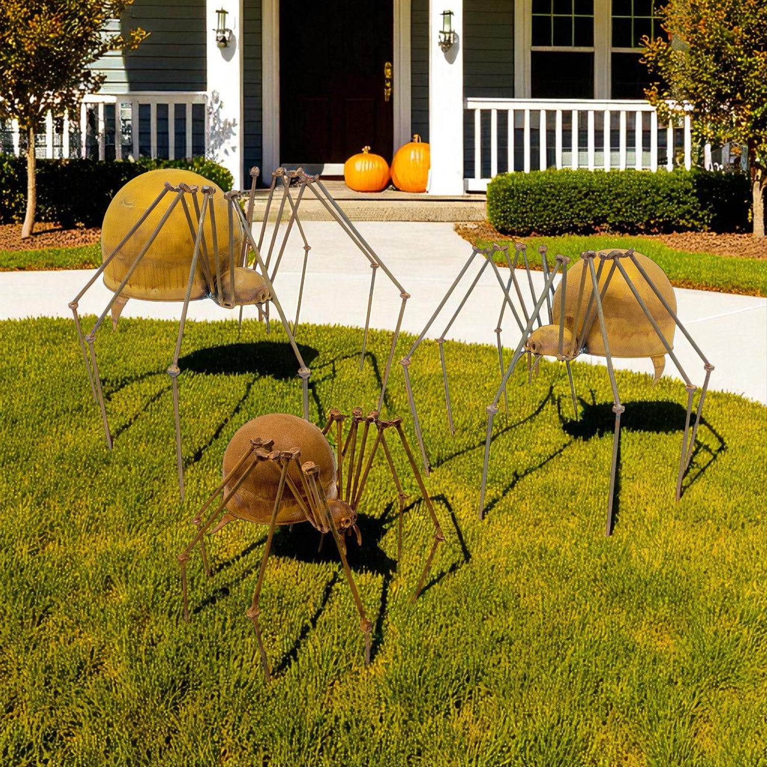 Set of three metal spider garden sculptures with distressed iron finish displayed on lawn