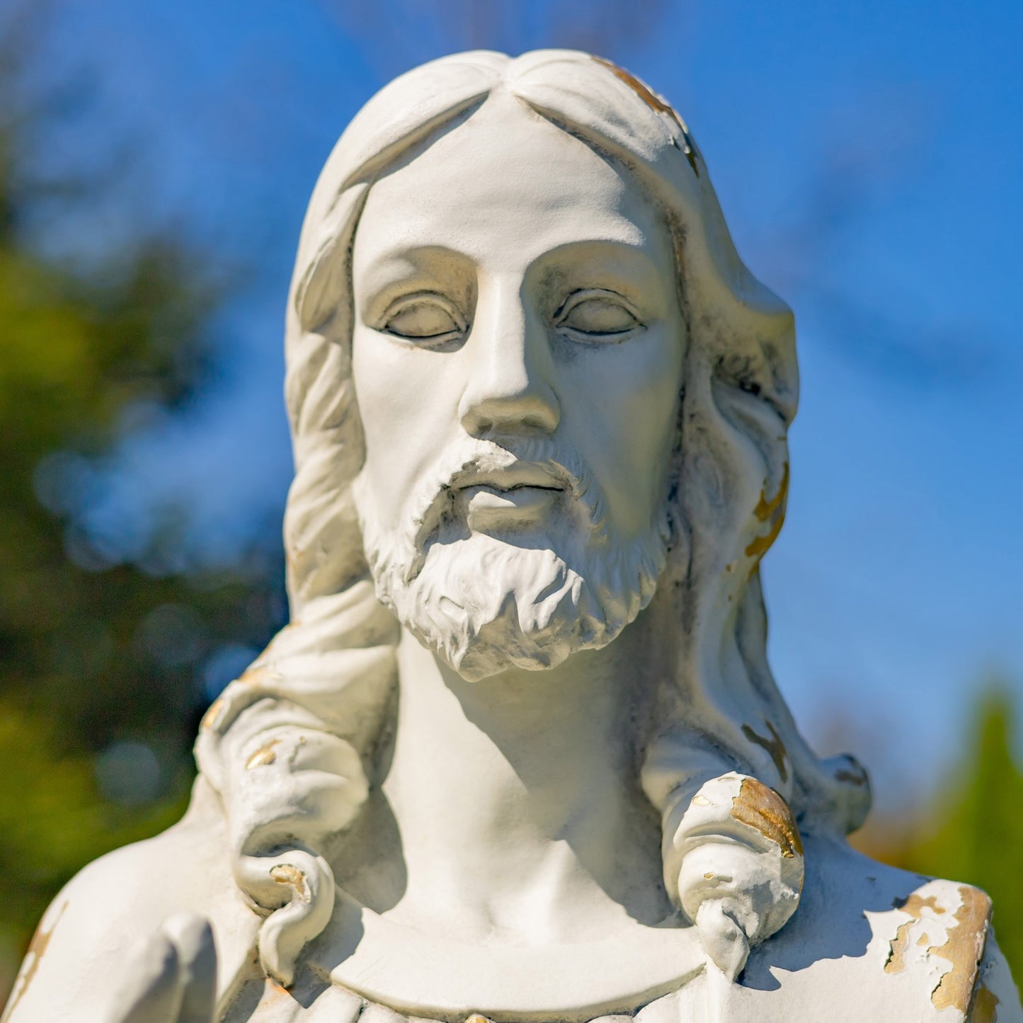 Tall Jesus with Sacred Heart Statue in garden setting close up of face