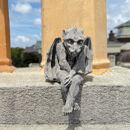 Gargoyle statue on a building with columns in the background