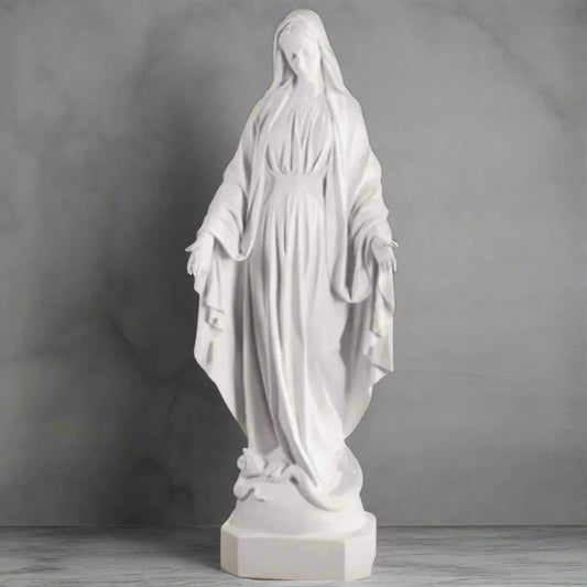 Bonded marble Virgin Mary statue, life-size and serene, shown outdoors with flowers and greenery surrounding a memorial-style base