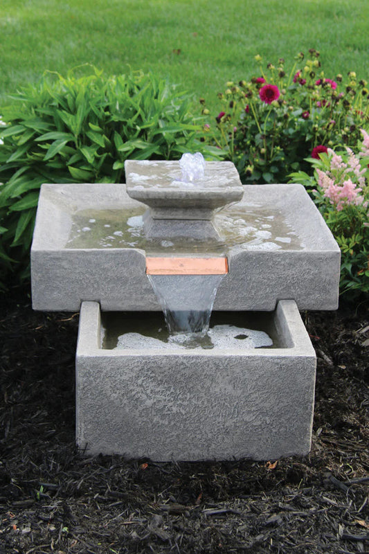 Two-tiered stone fountain with water feature in a garden setting