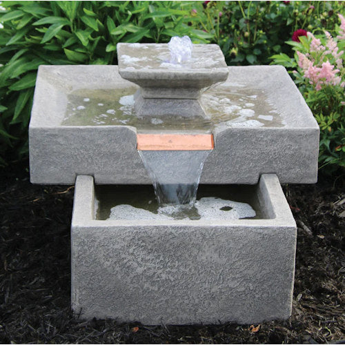 Stone garden fountain with water feature surrounded by greenery