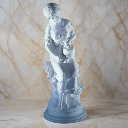 25.25-inch Italian marble Maiden with Jug statue, displayed in an outdoor garden with trimmed greenery.