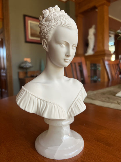 White classical bust on a wooden surface with a blurred background