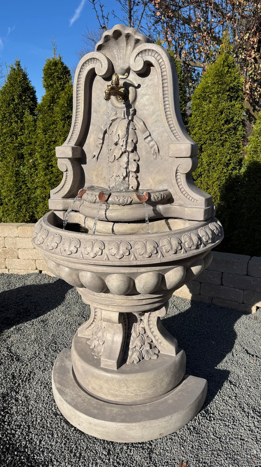 Cast stone flat back wall fountain with arched shell crest egg and dart bowl