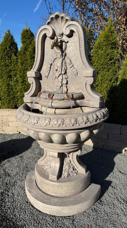 Cast stone flat back wall fountain with arched shell crest egg and dart bowl