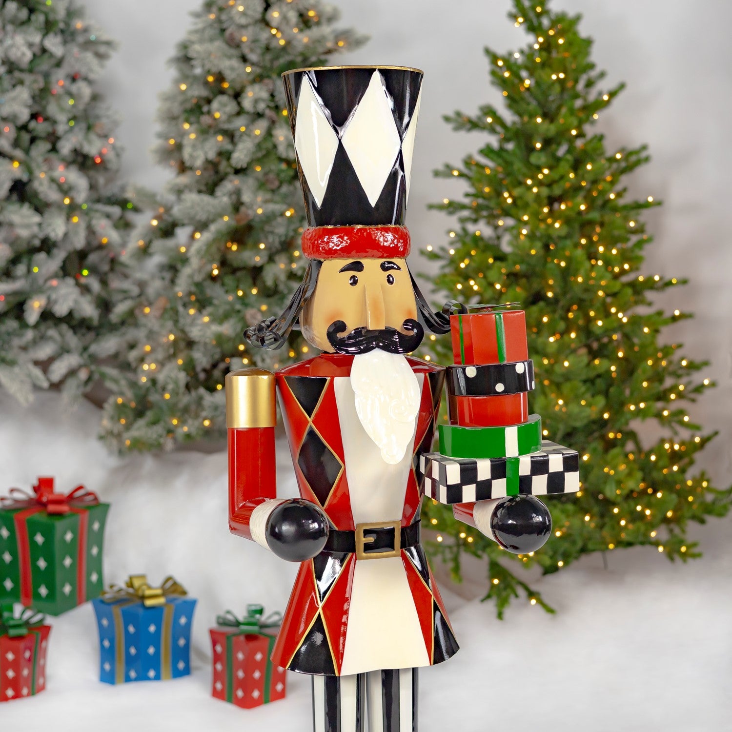 Decorative nutcracker figure with gift boxes in front of Christmas trees.