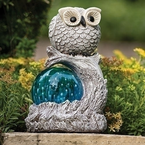 Decorative owl solar light figurine with a blue glass ball on a natural base, set against a garden background.