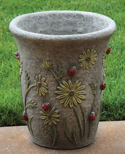 Decorative stone planter with floral and ladybug designs on a grass background
