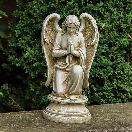 Statue of an angel with outstretched wings on a pedestal against a green foliage background