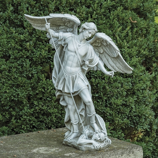 Saint Michael Garden Statue of an angel with a sword and shield against a green bush background