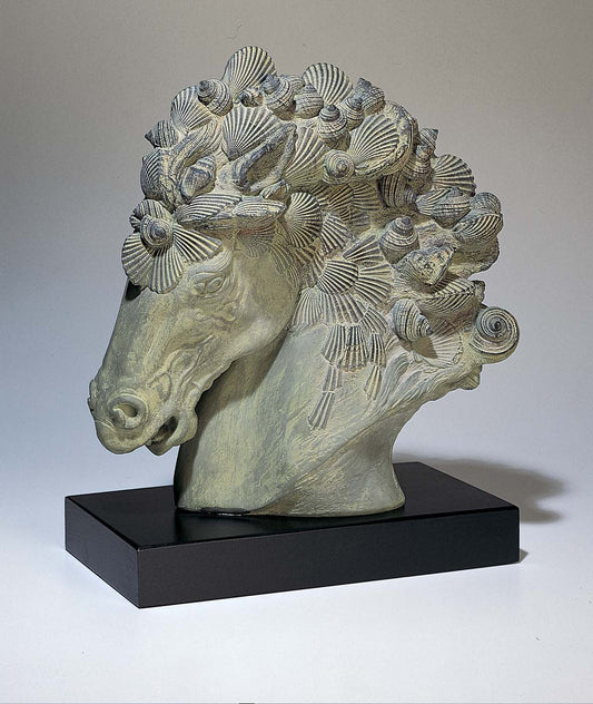 Decorative horse head sculpture with shell-like patterns on a black base against a neutral background