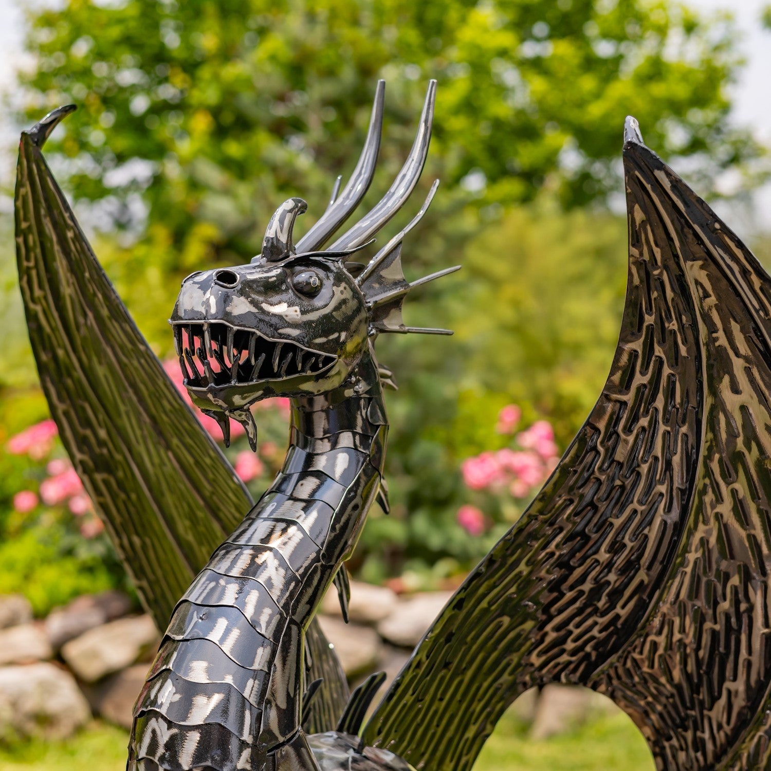 Metallic dragon sculpture with detailed features in a garden setting