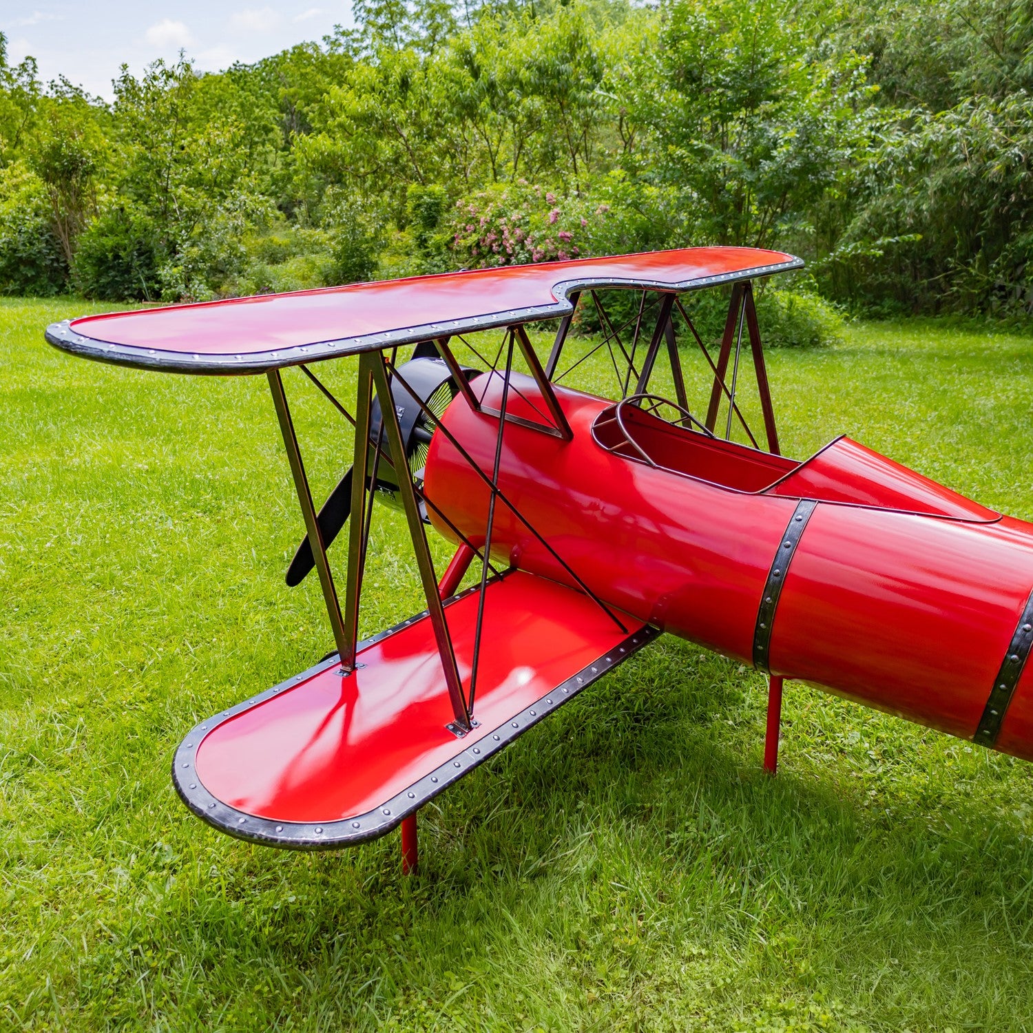 Huge 10-foot red metal biplane decorative sculpture with seat and LED lighting displayed on grass