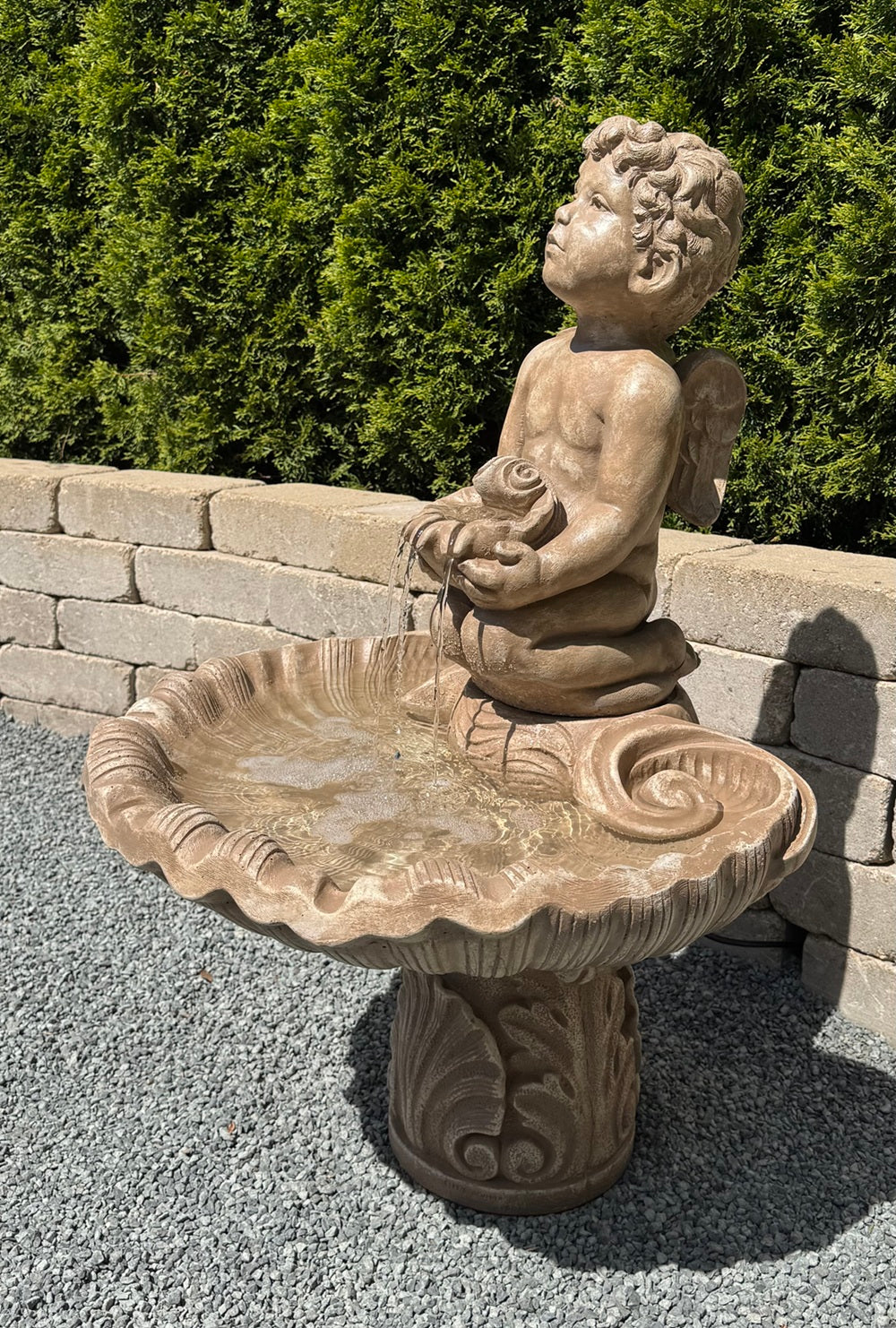 boy cherub garden fountain cast stone holding shell Italian inspired water feature side view of wings