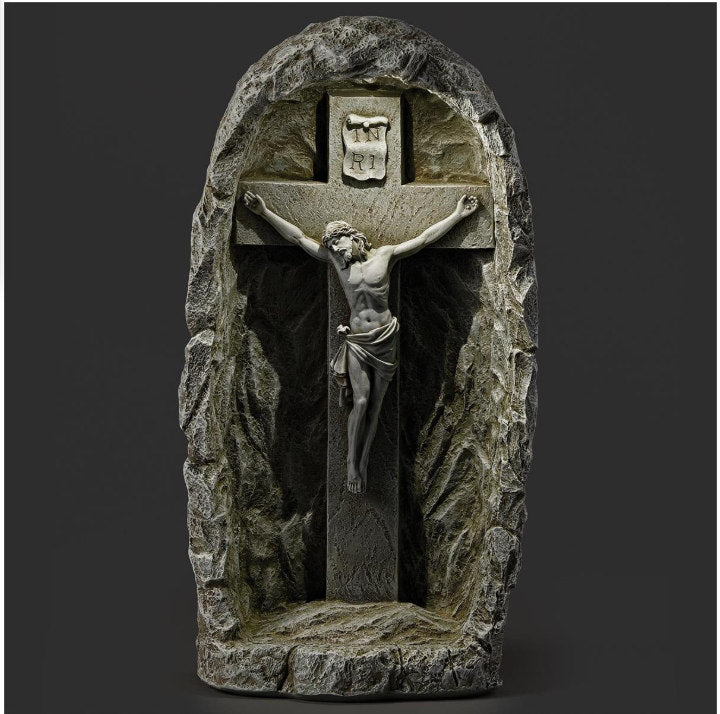 Outdoor Christian statue with illuminated crucifix at night in grotto sculpture lighted