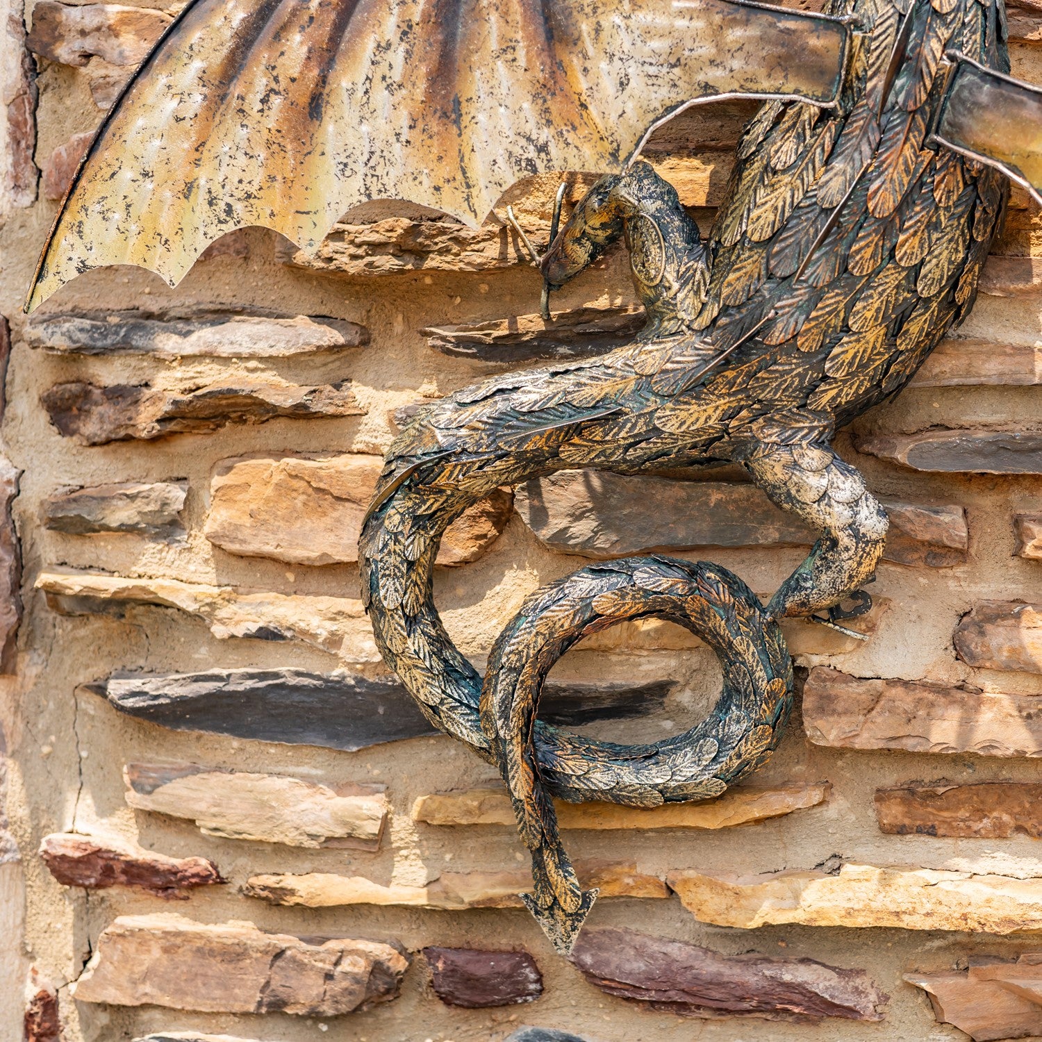 Tail close up Guardian Serpent wall dragon sculpture with coiled body and spread wings mounted on stone wall