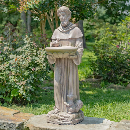 Statue of a religious figure holding a bird bath with a squirrel on a garden background