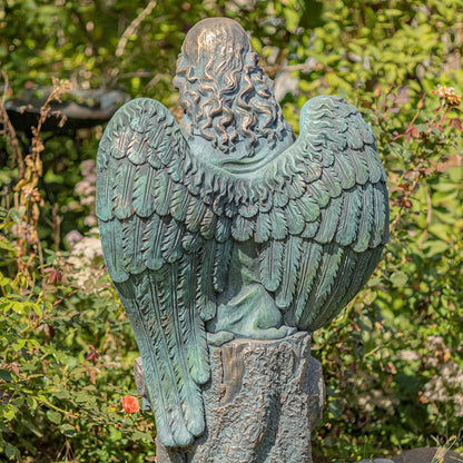 Bronze angel statue with detailed wings against a natural background