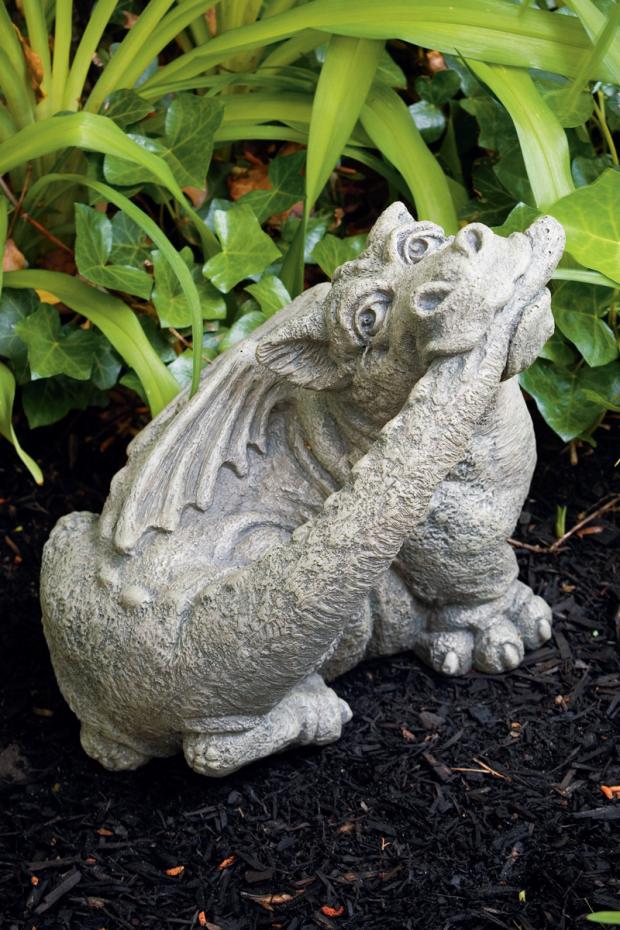 Stone  dragon statue in a garden setting with green foliage biting tail  sculpture