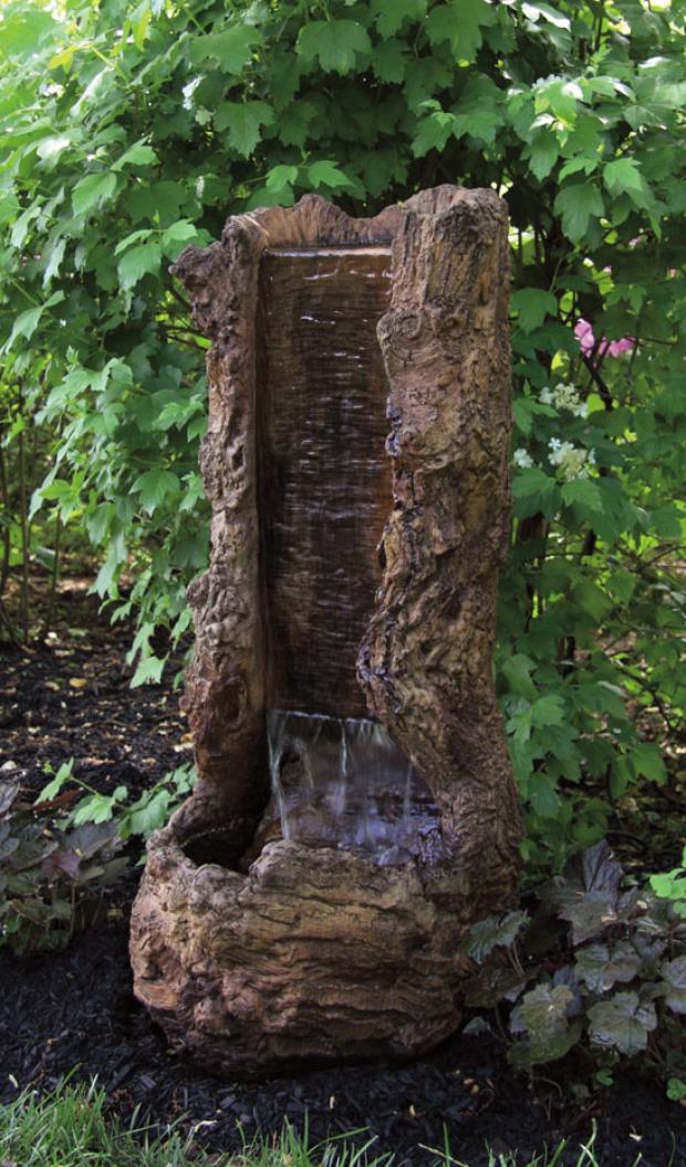 Decorative stone water fountain in a garden setting with green foliage.
