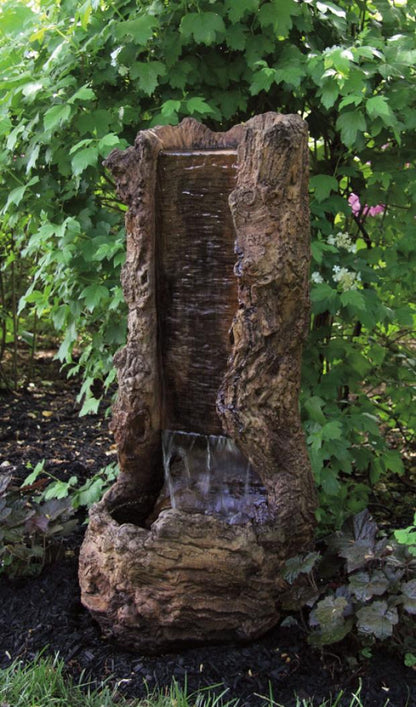 Decorative stone water fountain in a garden setting with green foliage.