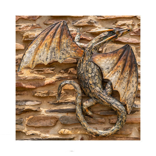 Relief Winged serpent dragon wall sculpture with textured scales and wide metal wings on stone wall