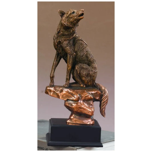This bronze-toned wolf sculpture captures a majestic wolf perched alertly on rocky terrain.