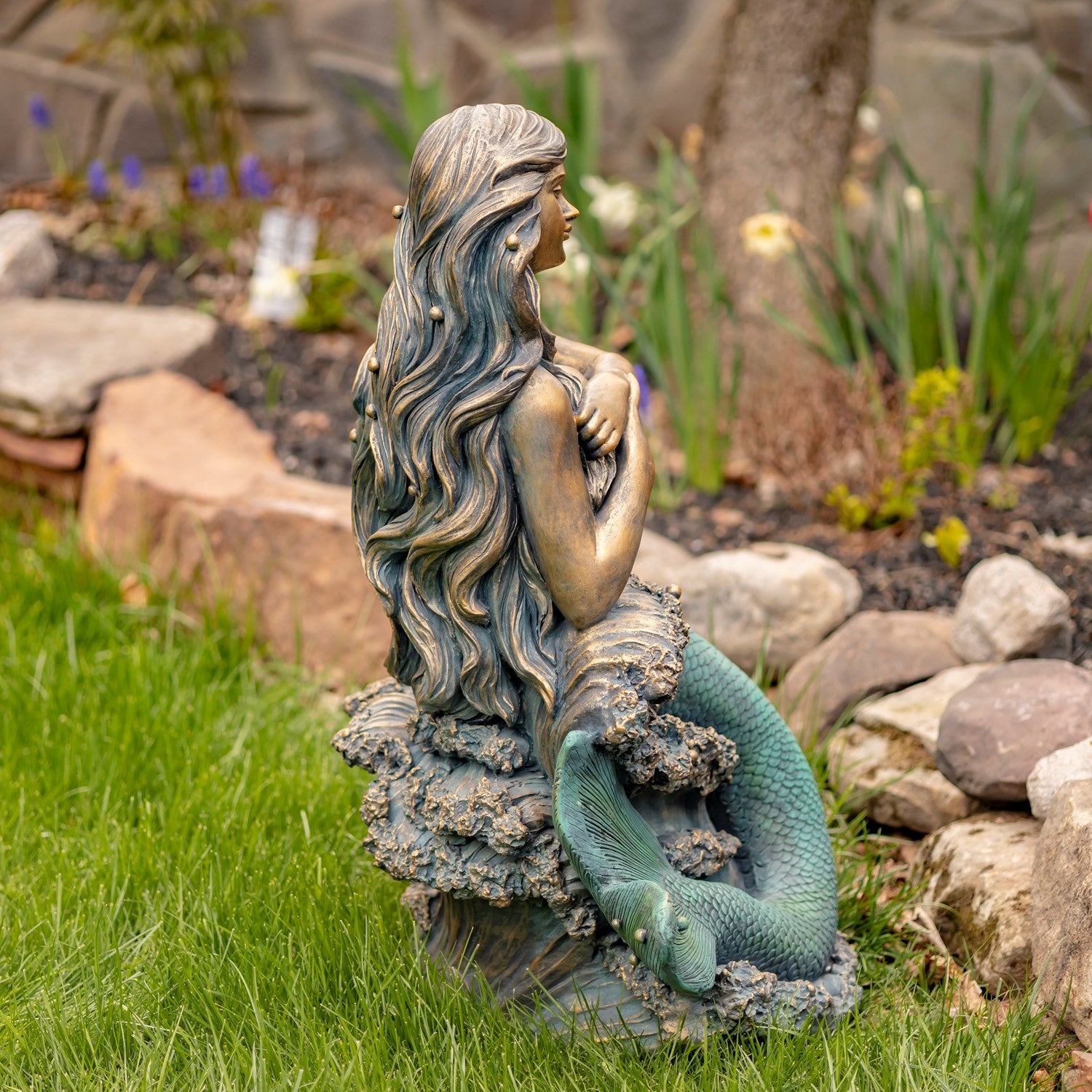 Detailed view of the mermaid statue base with textured rocks and sculpted ocean waves